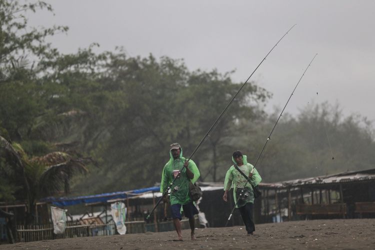 Pemancing lokal bergegas balik setelah hujan deras melanda di sekitar Pantai Petanahan yang terletak di Desa Karanggadung, Kecamatan Petanahan, Kabupaten Kebumen, Jawa Tengah, Senin (16/10/2017). Pantai Petanahan adalah salah satu obyek wisata pantai di Kebumen yang biasa dikunjungi wisatawan. KOMPAS.com/GARRY ANDREW LOTULUNG