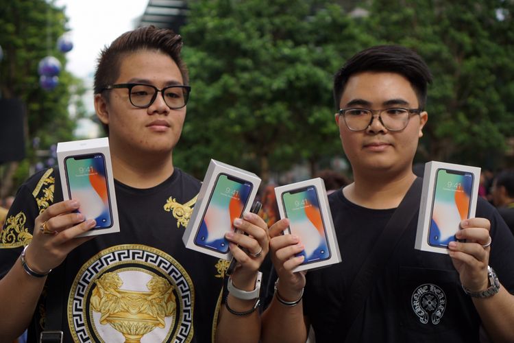 Pembeli pertama iPhone X di Apple Store Singapura Kittiwat Wang (kiri), dan temannya, Supakorn Rieksiri, menunjukkan empat unit iPhone X yang mereka beli, Jumat (3/11/2017).