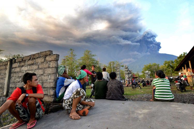 Warga Bali menonton erupsi Gunung Agung terlihat dari Kubu, Karangasem, Bali, 26 November 2017. Gunung Agung terus menyemburkan asap dan abu vulkanik dengan ketinggian yang terus meningkat, mencapai ketinggian 3.000 meter dari puncak. Letusan juga disertai dentuman yang terdengar sampai radius 12 kilometer.