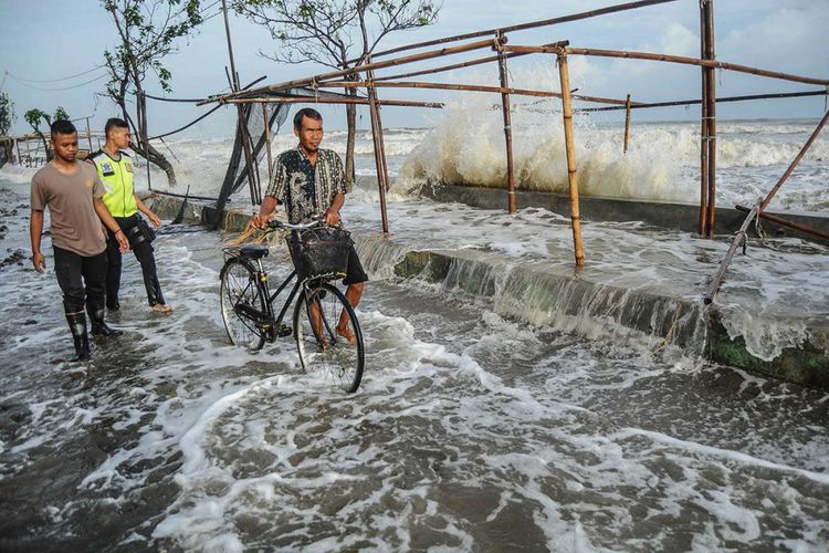 Sejumlah warga menghindari gelombang laut yang mengenai garis pantai di Pantaisari, Pekalongan, Jawa Tengah, Jumat (1/12/2017). Gelombang laut setinggi sekitar 2,5-6 meter dan curah hujan lebat disertai angin kencang yang dipicu siklon tropis Dahlia menyebabkan sejumlah titik di kawasan Pekalongan Utara banjir.