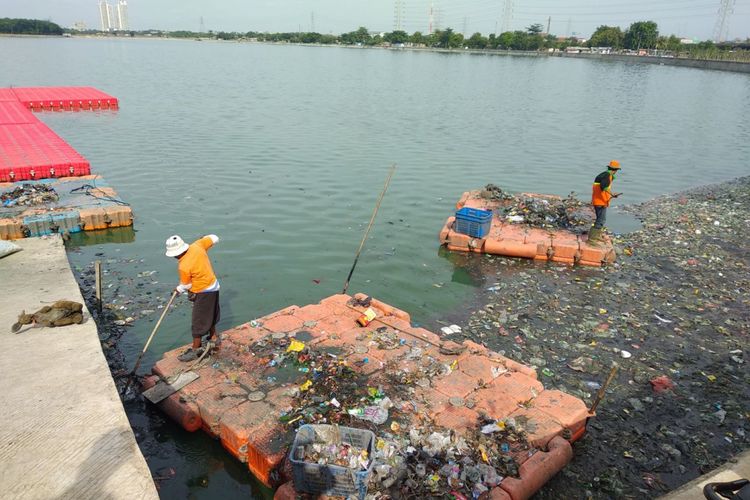 Petugas kebersihan membersihkan permukaan waduk Cincin, Papanggo, Jakarta Utara dari sampah, Minggu (10/12/2017)