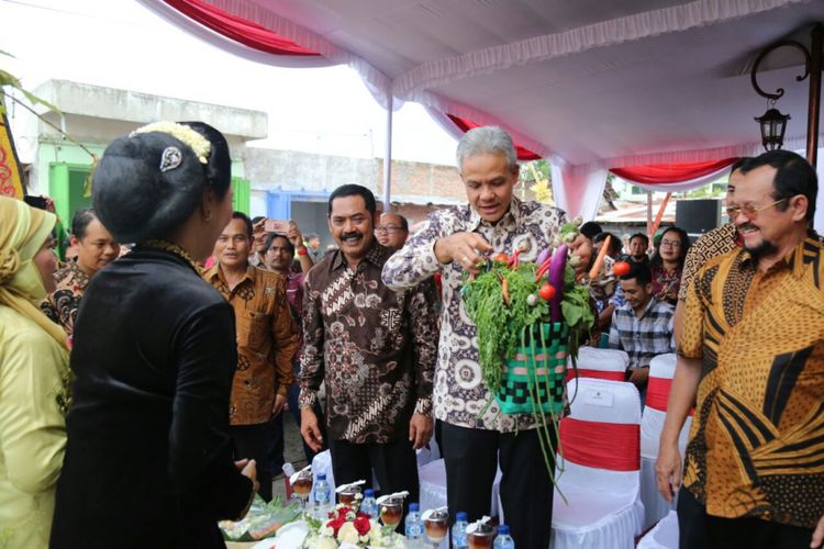ANGKAT--Gubernur Jawa Tengah, Ganjar Pranowo mengangkat keranjang berisi sayuran setelah meresmikan dan berbelanja di Pasar Rejosari - Jebres, Kota Solo , Sabtu (30/12/2017).