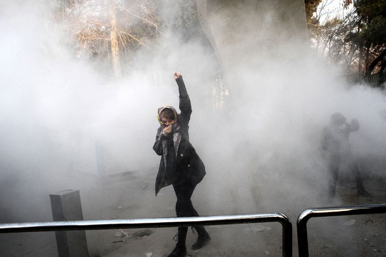Seorang wanita mengangkat tangannya di tengah kepulan gas air mata saat mengikuti aksi demo di Universitas Teheran, Ibu Kota Teheran, Sabtu (30/12/2017). Unjuk rasa anti-pemerintahan Presiden Hassan Rouhani di Iran berlangsung hampir sepekan, memakan korban tewas hingga puluhan orang dan ratusan orang ditangkap pihak keamanan.