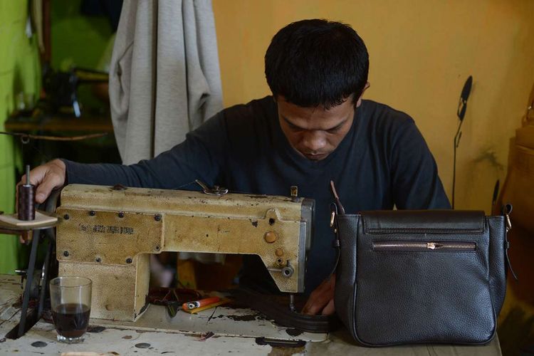 Pekerja menjahit bahan kulit yang akan digunakan untuk membuat produk seperti tas, alas kaki, jaket atau aksesori mode di pusat industri rumahan di Garut, Jawa Barat, Selasa (26/12/2017). Produsen kerajinan kulit di Indonesia sebagian besar adalah industri usaha kecil dan menengah yang berlokasi di Jawa Barat dan Jawa Timur dengan 20 sampai 100 karyawan.