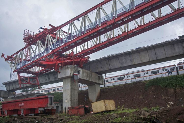 KRL melintas di samping crane proyek pembangunan kontruksi  jalur rel dwi ganda atau double-dobel track (DDT) yang roboh di Jalan Slamet Riyadi, Matraman, Jakarta, Minggu (4/2/2018). Crane dari proyek pembangunan rel Jakarta-Cikarang itu roboh pada Minggu (4/2/2018) sekitar pukul 05.30 WIB dan menyebabkan empat pekerja proyek tersebut tewas.