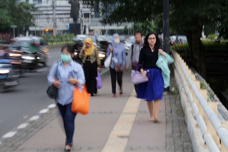Sejumlah warga melintas di Trotoar Jalan Sudirman, Jakarta, Jumat (09/03/2018). Gubernur DKI Jakarta Anies Baswedan akan merevitalisasi trotoar sepanjang Jalan Sudirman-Thamrin. Trotoar  tersebut akan diperlebar hingga 8 meter dan akan dilengkapi titik-titik pertunjukan seni budaya.