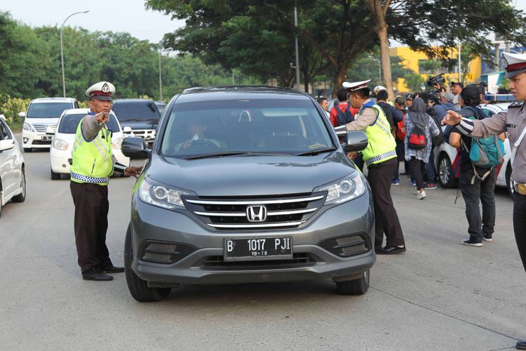 Petugas kepolisian mengarahkan kendaraan yang melintas saat uji coba sistem ganjil genap di Pintu Tol Kunciran 2, Tangerang, Banten, Senin (16/4/2018). Kepala Badan Pengelola Transportasi Jabodetabek (BPTJ) Bambang Prihartono menargetkan, kebijakan sistem ganjil-genap di tol Tangerang-Jakarta bisa mengurangi kepadatan menuju Jakarta hingga 50 persen.