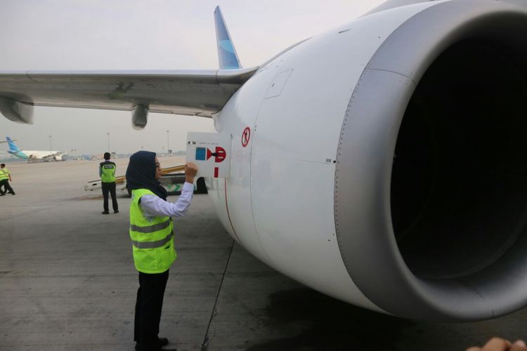 Staf teknisi perempuan Garuda Indonesia memeriksa bagian pesawat.