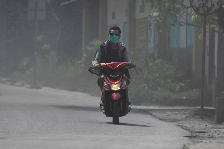Pengendara sepeda motor mengenakan masker saat melintas di kawasan Dukun, Magelang, Jawa Tengah, Rabu (23/5/2018).