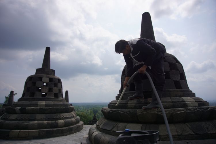 Seorang petugas membersihkan abu vulkanik Gunung Merapi yang menempel di stupa candi Borobudur, Kamis (24/5/2018),