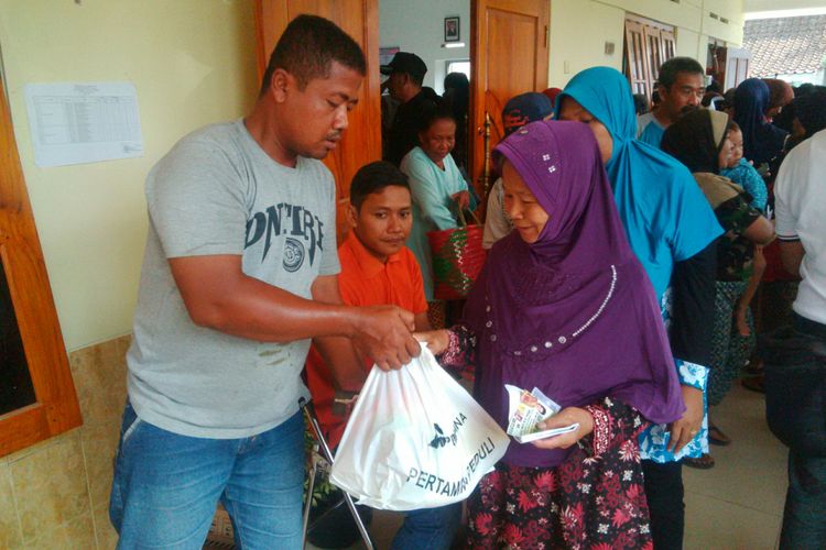 Seorang warga membawa peket sembako yang dibagikan di Kelurahan Gedaren, Jatinom, Klaten, Jawa Tengah, Jumat (25/5/2018).