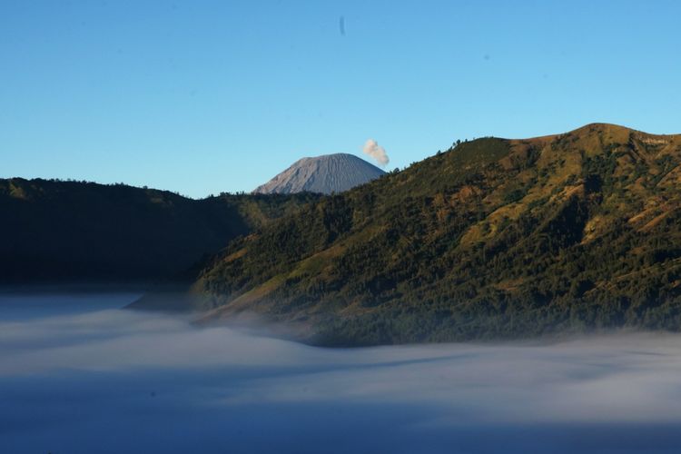 Gunung Semeru terlihat dari titik pengamatan matahari terbit di kawasan wisata Gunung Bromo di Bukit Mentigen, Desa Ngadisari, Probolinggo, Jawa Timur, Kamis (7/6/2018). Lokasi wisata tersebut menjadi tujuan favorit wisata karena panorama alamnya yang menjadi magnet wisatawan lokal maupun mancanegara.