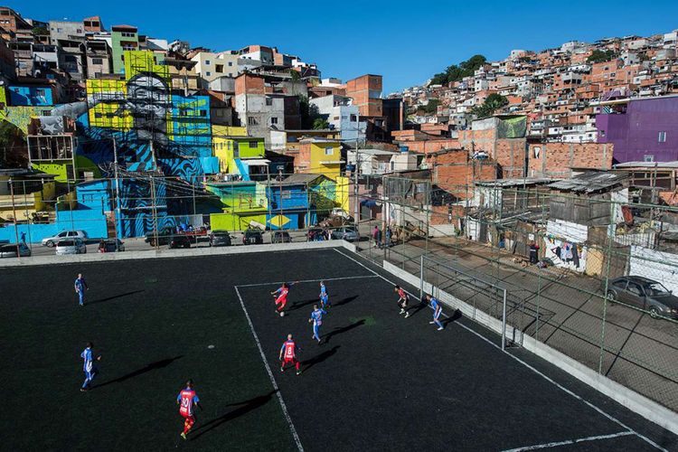 Foto diambil pada 20 Mei 2018, memperlihatkan warga bermain bola di lapangan dengan latar belakang gambar pemain sepak bola Brasil Gabriel Jesus yang dicat di dinding rumah-rumah di kawasan Perus, Brasil. Ada sejumlah lapangan sepak bola unik yang berdiri di berbagai penjuru dunia, mulai dari konstruksi bangunan hingga pemilihan lokasi yang tak biasa tempat dibangunnya stadion tersebut.