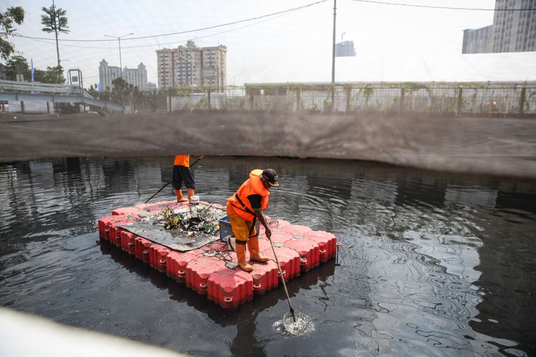 Pekerja membersihkan sampah di Kali Sentiong atau Kali Item, Jakarta Utara, Jumat (20/7/2018). Pemasangan jaring-jaring berbahan nilon untuk mengatasi buruknya rupa Kali Item sebelum menerima para atlet Asian Games 2018 dari mancanegara yang akan menginap di Wisma Atlet.