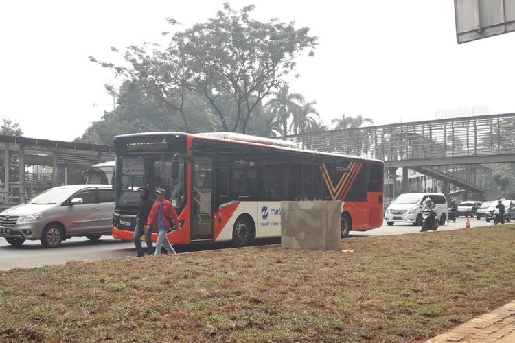 Sejumlah penumpamg turun di tepi Jalan Jenderal Sudirman, Selasa (24/7/2018).