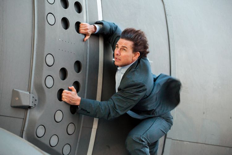 Aktor Tom Cruise berpegangan pada sisi sebuah pesawat yang hendak lepas landas dalam film Mission: Impossible - Rogue Nation.