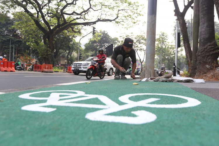 Pekerja akan memindahkan sejumlah tiang yang menghalangi jalur sepeda di Jalan Asia Afrika, Jakarta, Rabu (01/08/2018). Jalur sepeda di sepanjang jalan ini terhalang beberapa tiang lampu penerangan jalan umum (PJU), tiang lampu lalu lintas, hingga tiang rambu penunjuk jalan.