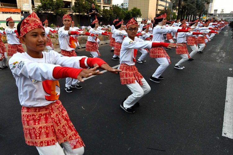 Para penari menampilkan tarian tradisional Poco-poco di sepanjang jalan  MH Thamrin, Jakarta, Minggu (5/8/2018). Sebanyak 65.000 orang penari turut serta dalam pemecahan rekor dunia tarian Poco-poco dan juga merupakan promosi menjelang Asian Games 2018.