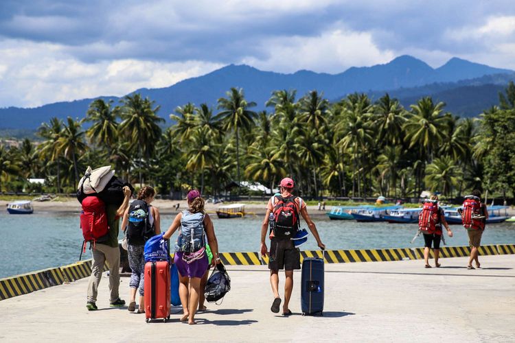 Wisatawan mancanegara membawa barang bawaanya menuju bus setelah tiba di Pelabuhan Bangsal, Lombok Utara, Nusa Tenggara Barat, Selasa (7/8/2018). Wisatawan, pekerja, dan warga dievakuasi dari Gili Trawangan, Gili Air, dan Gili Meno menuju Pelabuhan Bangsal untuk diberangkat ke Kota Mataram pascagempa Lombok hari kedua.