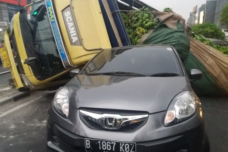 Truk bermuatan pisang seberat 6,5 ton menimpa mobil sedan di Jalan Pos Pengumben, Kembangan, Jakarta Barat pada Senin (13/8/2018).