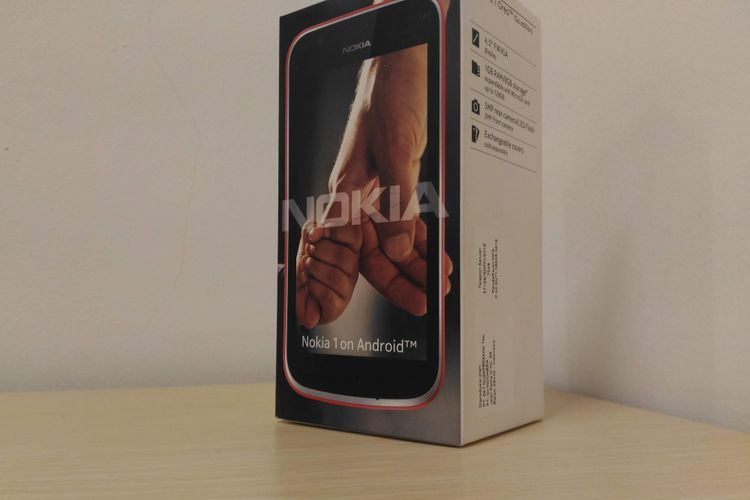 Kotak kemasan Nokia 1 dengan logo tangan anak kecil menggandeng jemari orang dewasa