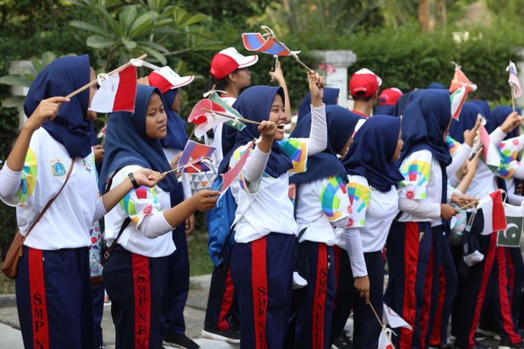 Sejumlah pelajar membawa bendera peserta Asian Games 2018 untuk menyambut Kirab Obor saat Torch Relay Asian Games 2018 di Cilandak, Jakarta Selatan, Rabu (15/08/2018). Api Asian Games akan diarak mengelilingi 5 Kota dan 1 Kabupaten di Provinsi DKI Jakarta