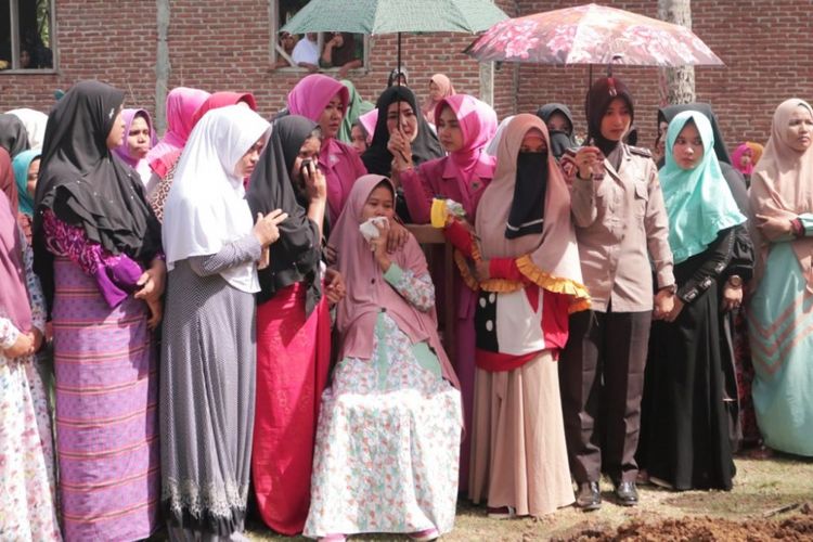 Siti Nur Rahmi (27) tak kuasa menahan tangis saat menyaksikan prosesi pemakaman, jenazah suaminya Bripka Faisal, di Desa Rambong, Kemukiman Beuracan, Kecamatan Meurudue, Kabupaten Pidie Jaya, Minggu (27/8/2018)