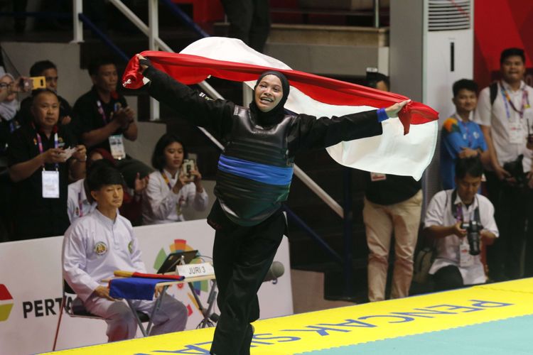 Pesilat Indonesia Sarah Tria Monita (sabuk biru) melakukan selebrasi usai mengalahkan pesilat  Laos Nong Oy Vongphakdy dalam babak final Kelas C Putri Asian Games 2018 di Padepokan Pencak Silat Taman Mini Indonesia Indah (TMII), Jakarta, Senin (27/8/2018). Sarah berhasil meraih medali emas cabang olahraga pencak silat kelas 55-60 kilogram.