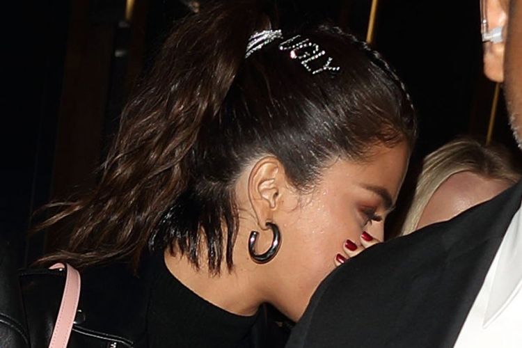Selena Gomez memakai jepit rambut berbentuk tulisan ugly.