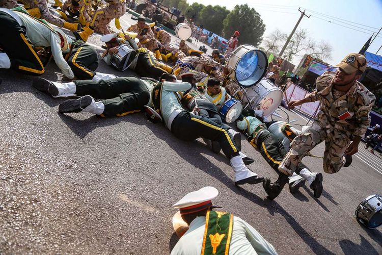 Seorang tentara berlari melewati rekan-rekannya yang terluka dan tergeletak di tanah saat terjadinya serangan pada parade militer di Kota Ahvaz, Iran, Sabtu (22/9/2018). Serangan yang terjadi pada parade militer Iran untuk memperingati dimulainya perang 1980-1988 dengan Irak yang kala itu dipimpin Saddam Hussein tersebut menewaskan 29 orang dan membuat 57 orang lainnya terluka.