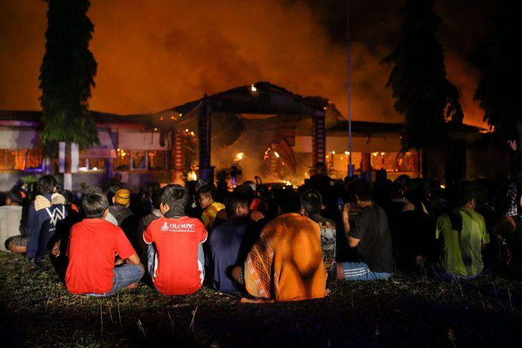 Narapidana dan tahanan dikumpulkan di halaman saat terjadi kebakaran di Rumah Tahanan Donggala, Sulawesi Tengah, Minggu (30/9/2018) pasca kerusuhan tahanan. Kerusuhan dipicu permintaan narapidana dan tahanan dibebaskan untuk menemui keluarga yang terkena musibah gempa tidak dipenuhi. Sekitar 100 tahanan dikabarkan melarikan diri.