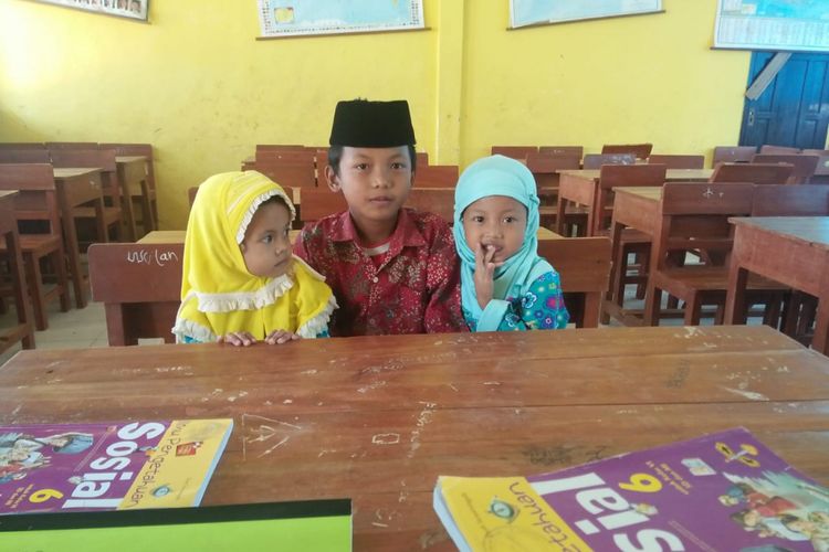 Ismail (11) siswa SDN Palenggiyan 1 sambil mengasuh kedua adiknya di sekolah. Di SDN Palenggiyan 1, anak-anak sekolah sambil mengasuh anak sudah turun temurun. 