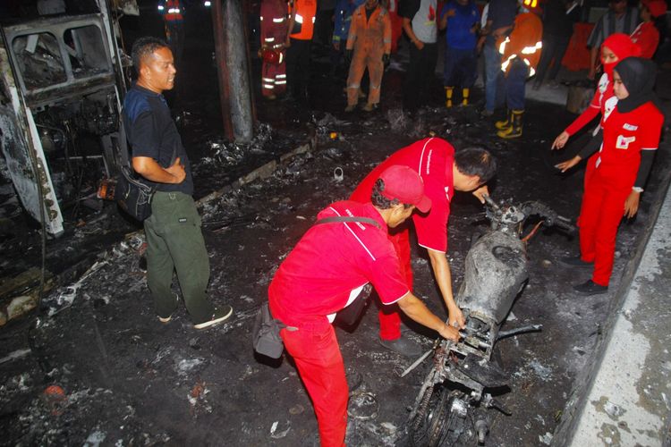 Sejumlah petugas sedang mengangkut sebuah motor yang hangus terbakar dalam peristiwa kebakaran di Pom Bensin Warung Jambu, Bogor, Jawa Barat, Kamis (11/10/2018).