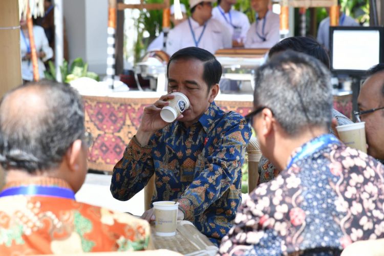 Presiden Joko Widodo beristirahat sejenak dengan meminum kopi di sela padatnya kegiatan di Bali Nusa Dua Convention Center, Jumat (12/10/2018).