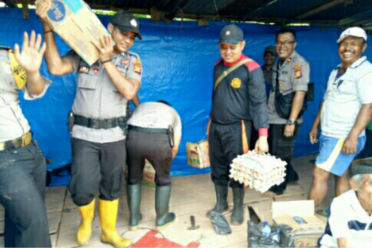 Petugas kepolisian jajaran Polres Rohil menyerahkan bantuan kepada korban banjir di wilayah Kecamatan Pekaitan, Rohil, Riau, Jumat (26/10/2018).