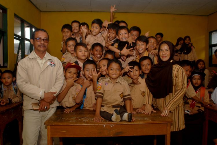 Mukhlis Abdul Holik alias Adul (duduk) berfoto bersama teman-teman sekelasnya diapit Kepala SDN X Cibadak Epi Mulyadi (kiri) dengan Wali Kelas 3 Euis Khodijah (kanan) di SDN X Cibadak, Desa Sekarwangi, Cibadak, Sukabumi, Jawa Barat, Sabtu (10/11/2018).