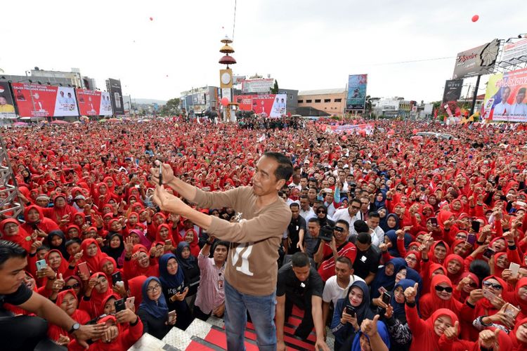 Calon presiden nomor urut 1 Joko Widodo saat berswafoto dengan latar belakang lautan massa di acara gerak jalan sehat di pusat kota Bandar Lampung, Sabtu (24/11/2018).