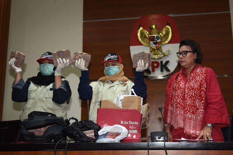 Wakil Ketua KPK Basaria Pandjaitan (kanan) menyaksikan petugas menunjukkan barang bukti uang yang diamankan dari operasi tangkap tangan (OTT) di Cianjur saat konferensi pers di Jakarta, Rabu (12/12/2018). KPK menetapkan empat tersangka termasuk Bupati Cianjur Irvan Rivano Muchtar, serta mengamankan uang sejumlah Rp1,556 miliar yang diduga merupakan hasil korupsi dari Dana Alokasi Khusus (DAK) Pendidikan Kabupaten Cianjur tahun 2018. ANTARA FOTO/Akbar Nugroho Gumay/kye.