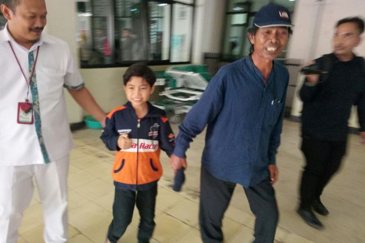 Tampak Asep Yaya (9) tengah digandeng ayahnya Subandi (56) saat pulang usai proses observasi pasca pengangkatan peluit yang bersarang di saluran pernafasan Asep.  