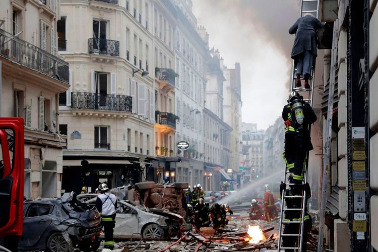 Pemadam kebakaran dengan menggunakan tangga menurunkan seorang warga di kawasan Rue de Trevise, Paris, ketika sebuah toko roti meledak akibat kebocoran gas pada Sabtu pagi (12/1/2019).