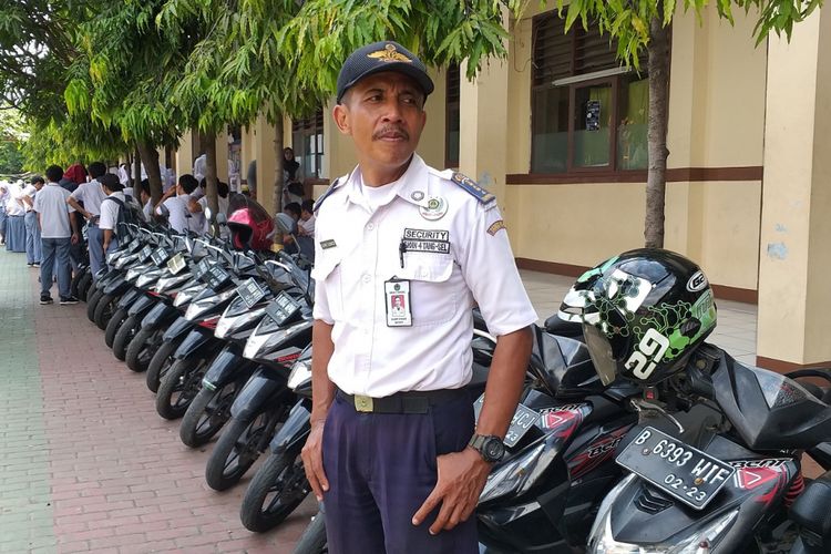 Satpam SMA Negeri 4 Tangerang Selatan, Slamet Gunaedi, berdiri di dekat barisan motor Honda BeAT, Senin (4/2/2019)