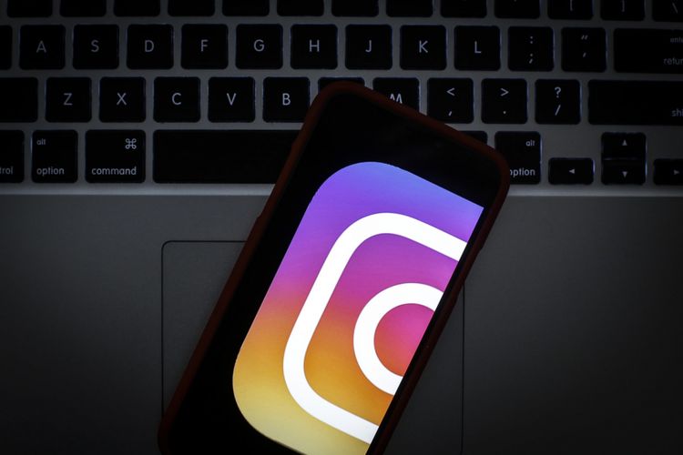 Ilustrasi logo Instagram pada ponsel yang terletak di atas laptop