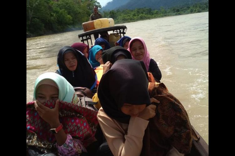 Siswa MAS Merdeka Tampor Paloh melintasi Sungai Tamiang menggunakan perahu kayu, Sabtu (16/02/2019). 
