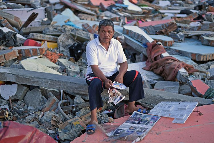 Sukur Sultan membawa foto keluarga yang meninggal akibat gempa dan tsunami di Wani, Donggala, Sulawesi Tengah, Selasa (9/10/2018). Para penyintas berusaha tegar untuk mencoba membangun kembali kehidupan pasca-gempa dahsyat yang disusul gelombang tsunami dan likuifaksi pada 28 September 2018 di sejumlah wilayah di Sulawesi Tengah.
