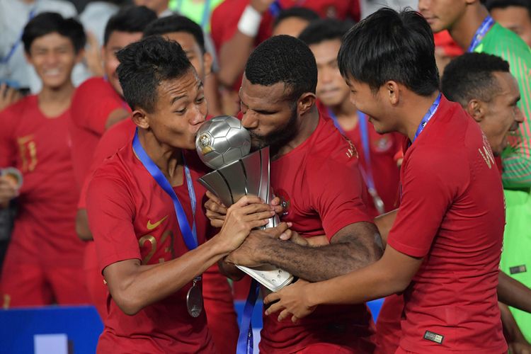 Pemain Timnas U-22 Sani Riski Fauzi (kiri) bersama Marinus Wanewar (tengah) mencium Piala AFF U-22 seusai penganugerahan piala di Stadion Nasional Olimpiade Phnom Penh, Kamboja, Selasa (26/2/2019). Indonesia menjadi juara setelah mengalahkan Thailand di babak final dengan skor 2-1.