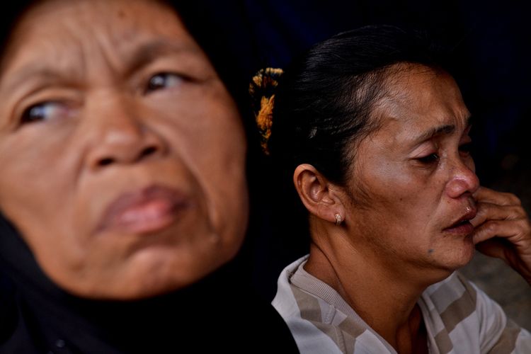 Dua orang wanita menanti kabar anggota keluarganya yang tertimbun longsor di lokasi Pertambangan Emas Tanpa Izin (PETI) Desa Bakan, Kecamatan Lolayan, Kabupaten Bolaang Mongondouw, Sulawesi Utara, Rabu (27/2/2019). Sebanyak 23 orang penambang tertimbun longsor, 19 orang di antaranya selamat dan 4 orang tewas.