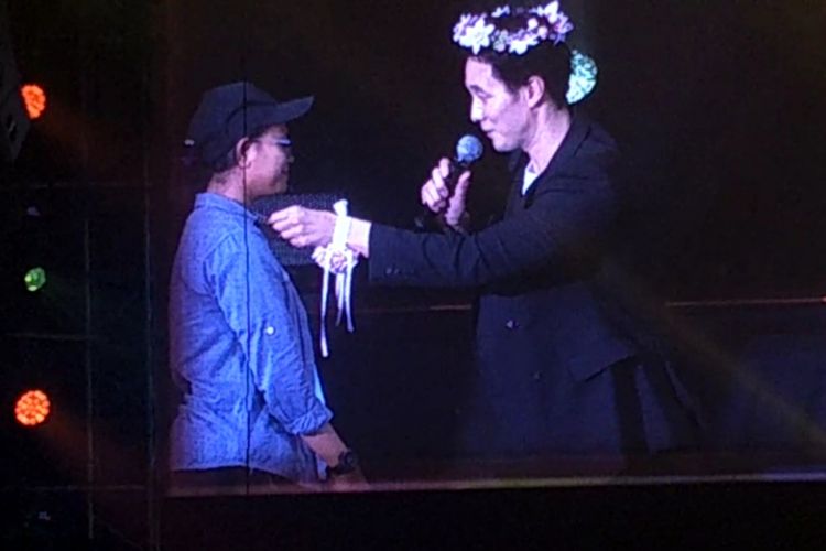 Aktor Korea Selatan So Ji Sub memakaikan kalung hadiahnya kepada seoranh penggemar yang beruntung dalam fan meeting Hello Jakarta di Balai Sarbini, Jakarta Selatan, Sabtu (9/3/2019).