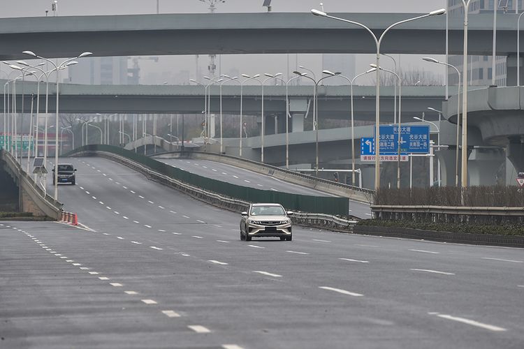 Sebuah mobil melintas di jalanan kota Wuhan, China, yang sepi karena wabah virus corona yang mematikan di hari pertama tahun baru Imlek, Sabtu (25/1/2020). 