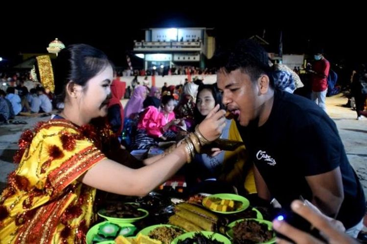 Seorang gadis yang mengenakan baju adat Buton, menyuapkan makanan kepada seorang tamu pria. Ini merupakan kegiatan tradisi kande tompa, atau tradisi mencari jodoh yang dilakukan masyarakat Kelurahan Tolandona, Kecamatan Sangia Wambulu, Kabupaten Buton Tengah, Sulawesi Tenggara