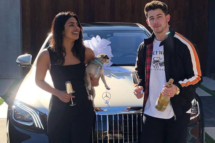 Pasangan suami istri Nick Jonas dan Priyanka Chopra berpose di depan mobil mewah mereka.